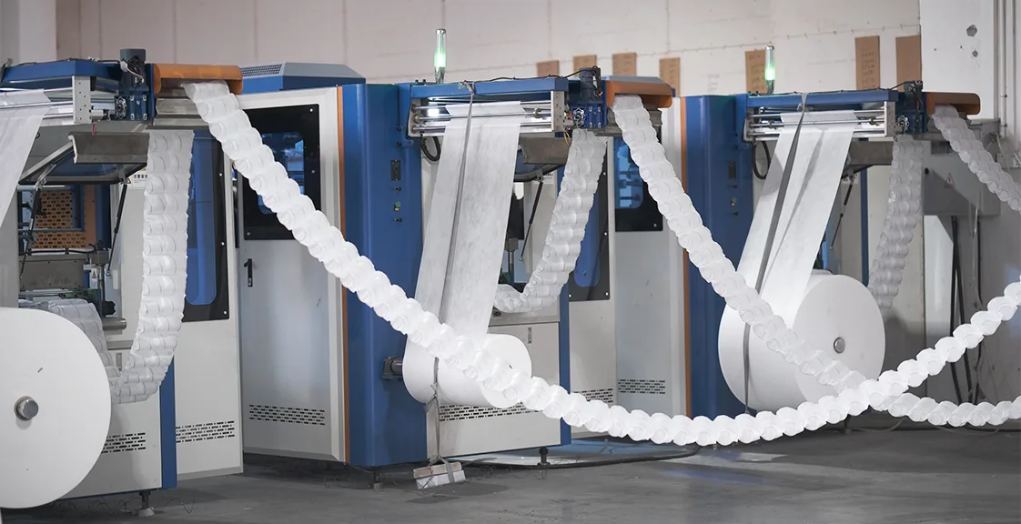 Automated pocket spring mattress machine in a mattress factory, showing coil forming and fabric pocket sealing process